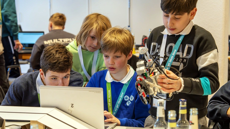 Schüler mit Roboter und Laptop nehmen Anpassungen an der Programmierung vor