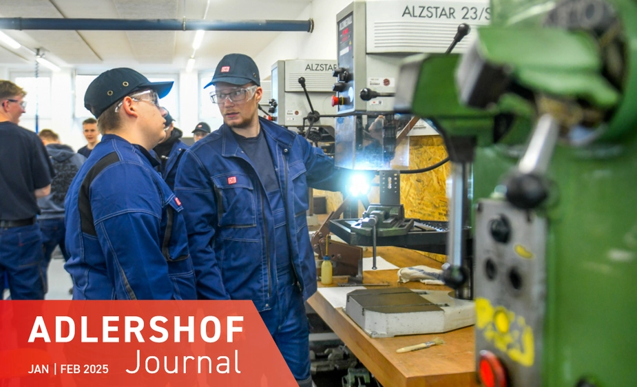 Two men in front of a machine in the metalworking area