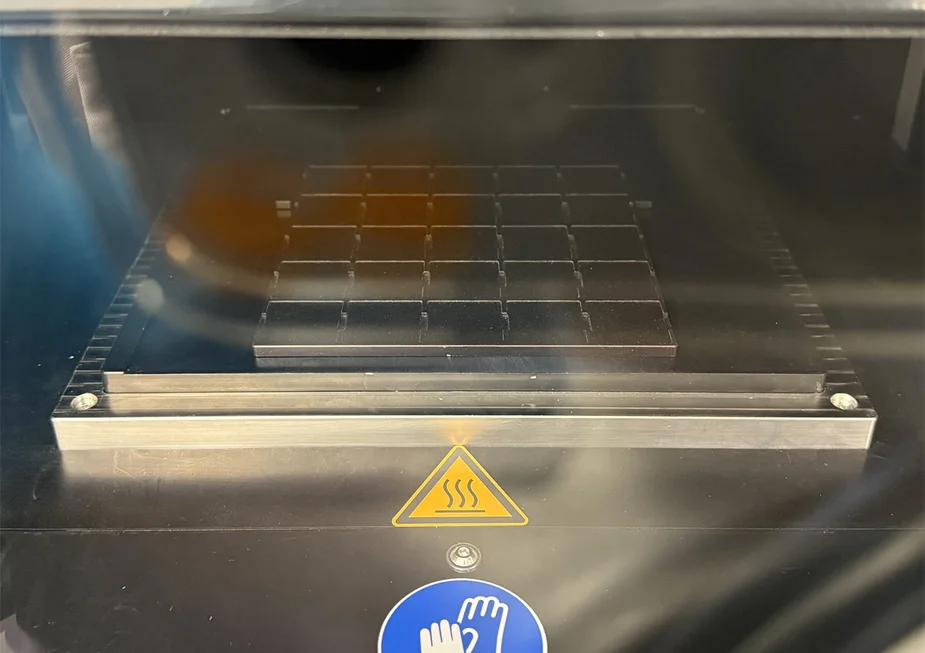 Metallplatte mit Raster für 25 Proben hinter einer Glasscheibe