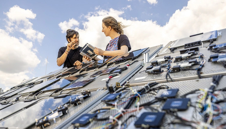 Two people at a system with lots of small solar cells