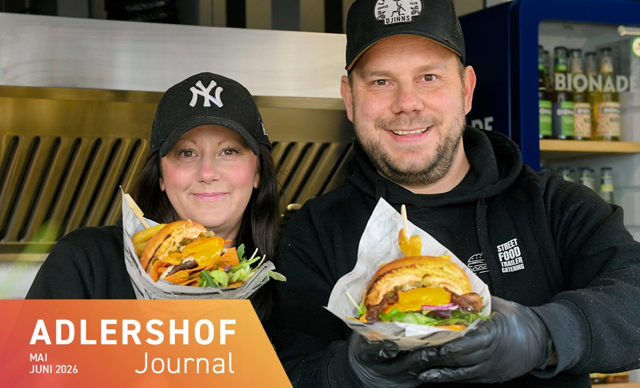 Mann und Frau mit Basecaps halten reich belegte Burger in den Händen