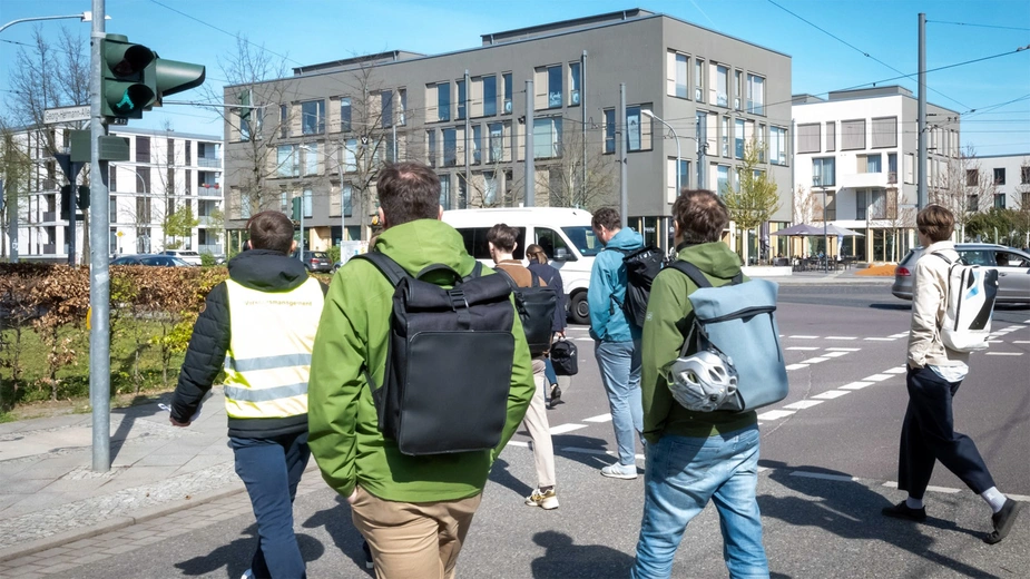 Mehrere Menschen überqueren eine Straße an einer Ampel in einer Stadt.