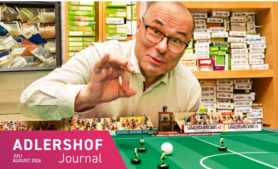 Giovanni Bruno at a table with table football figures, with lots of boxes on the shelf behind him