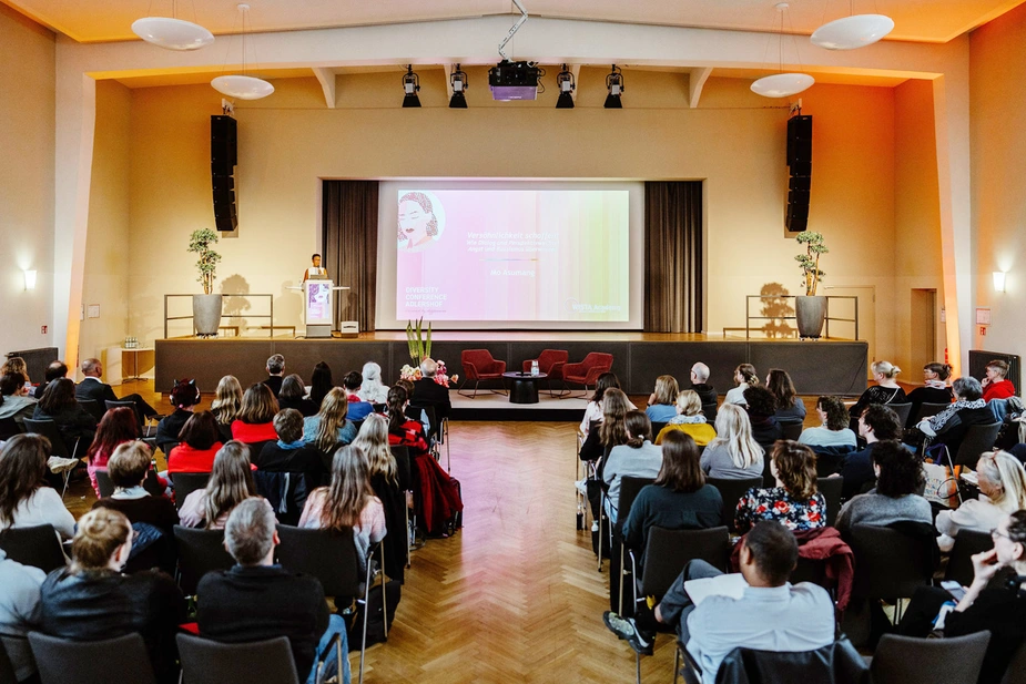Mo Asumang auf der Bühne im Bunsen-Saal vor dem Publikum.