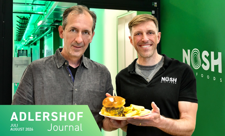 Two men holding a plate of burgers and chips
