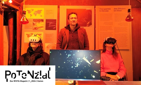 Christian Stein stands behind two visitors who are experiencing virtual worlds with VR headsets.