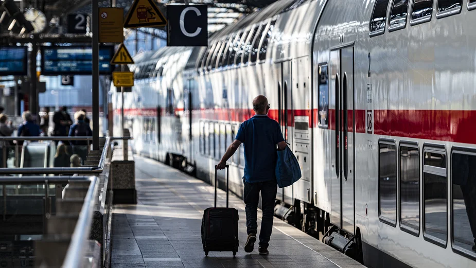 Mann mit Rollkoffer an einem Zug