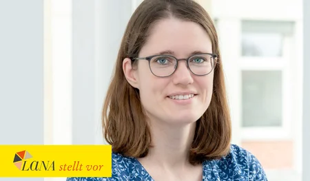 Frau mit schulterlangen braunen Haaren und Brille lächelt in einem hellen Raum