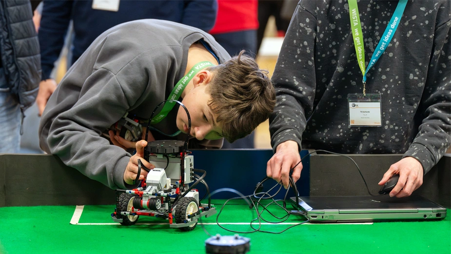 Schüler positioniert seinen Fußball-Roboter auf dem Spielfeld