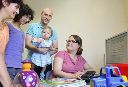 Elternschaft und Beruf können die Physiker Andrea Lübke (r.) und Faruk Krecinic, hier mit Tochter Emina im Familienzimmer des MBI, gut managen, auch dank der Unterstützung durch die Gleichstellungsbeauftragten Claudia Reschke (2. v. l.) und Margret Rin. Bild: © Adlershof Journal 