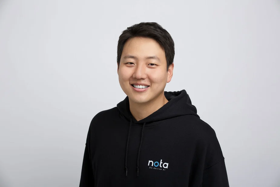 Seul-Ki Yeom mit schwarzem Kapuzenpullover mit weiß-blauem Schriftzug vor weißem Hintergrund